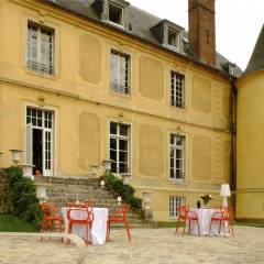Façade arrière du château avec sa tourelle et sa terrasse pavée.