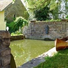 Un ancien canoë en bois sur la margelle du bassin au triton.